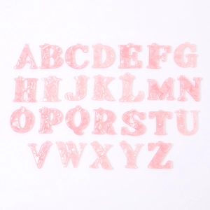 Flat lay of 26 light pink marble texture acrylic alphabet pendants for DIY crafts