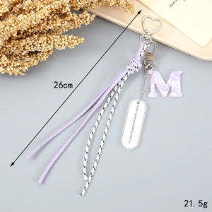Detail of purple woven tassel keychain with marble M letter and heart-shaped metal clasp