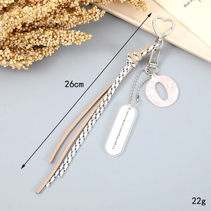 Detail of bohemian woven rope keychain with pink glitter O-letter and engraved oval pendant