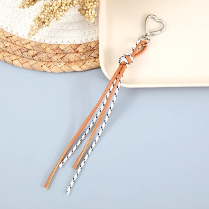 Détail d'un bijou de téléphone en corde tissée avec fermoir coeur et pompons en cuir