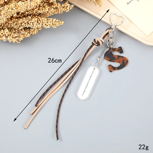 Detail of woven rope keychain with brown leather strap and tortoise letter S pendant