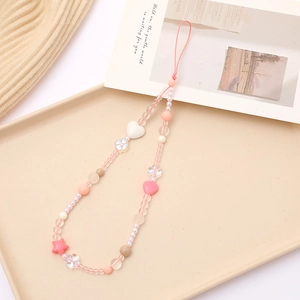 Pink heart and star beaded acrylic phone charm strap with floral accents on a tray