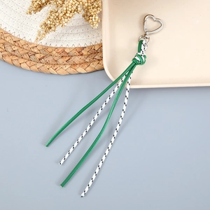 Détail de porte-clés en corde tressée avec attaches en forme de cœur argenté sur fond naturel