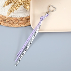 Détail du cordon tressé avec fermoir cœur en argent sur des cordes violettes et noires