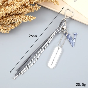 Detail of woven rope keychain with blue marble letter V and leather tassel accessory
