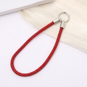 Detail of red rhinestone phone chain with a silver circular spring clasp and silk background