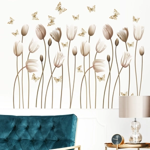 Stickers muraux tulipes blanches et papillons dorés au-dessus d'un canapé en velours bleu