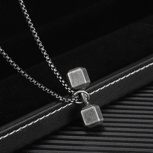 Macro shot of dumbbell pendant on vintage box chain with matte silver finish