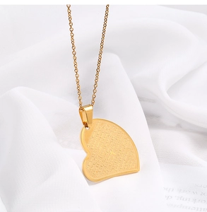 Détail du pendentif cœur doré avec le Notre Père gravé au laser et symbole de croix