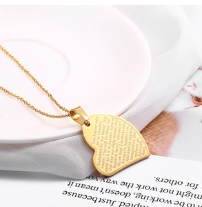 Vue détaillée du pendentif coeur doré avec gravure du Notre Père et d'une croix