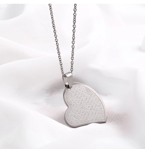 Détail du pendentif cœur avec gravure du Notre Père sur chaîne en acier inoxydable argenté