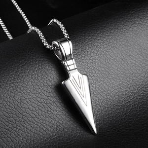 Macro shot of silver arrowhead pendant with V-shaped engraving on black leather background