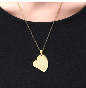 Gros plan d'un collier pendentif cœur doré avec le Notre Père et une croix gravée