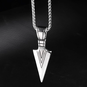 Detailed macro shot of vintage silver arrowhead pendant with intricate mesh engraving