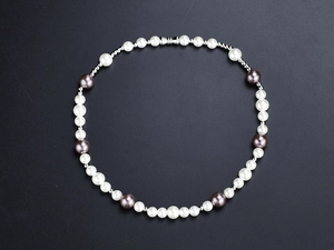 Detail view of hip hop necklace with alternating white and dark grey pearls on black base