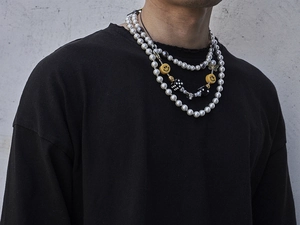 Detail of layered hip-hop necklace with smiley face and dice charms on a model