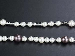 Macro detail of vintage pearl necklace with metallic spacers and matte magnetic clasp