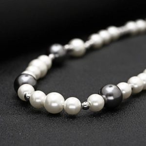 Detail of alternating white and dark grey pearls on a metallic beaded street style necklace