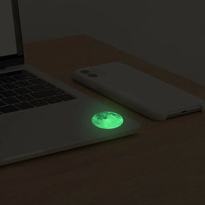 Detailed view of luminous green moon wall sticker glowing on a laptop surface