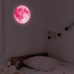 Detailed view of a 30cm pink luminous moon wall sticker glowing in a dark bedroom