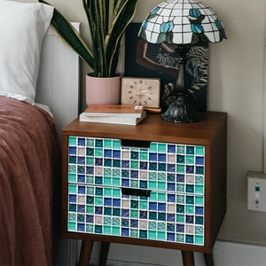 Autocollants de carreaux mosaïque bleu et vert sur un tiroir de chevet en bois foncé