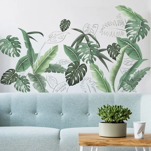 Stickers muraux feuilles tropicales et monstera sur mur blanc au-dessus d'un canapé