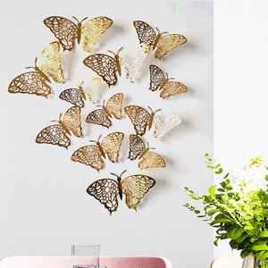 Adhesivos de pared de mariposas 3D doradas con patrones florales y abejas en pared blanca