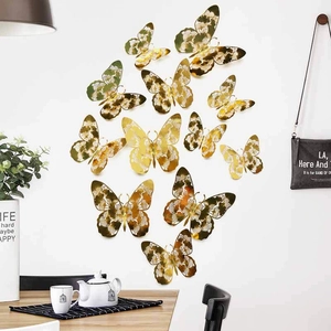 Set of 12 golden hollow butterfly wall stickers with intricate patterns on white wall
