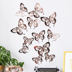 Detailed view of 3D rose gold hollow butterfly wall stickers on a clean white wall