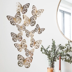 12er-Set goldene Hohl-Schmetterling-Wandtattoos mit filigranem Laserschnitt auf einer weißen Wand