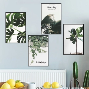 Detailed close-up of four-piece tropical plant wall art with black frames on blue wall