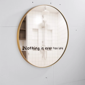 Detail of round gold mirror featuring Nothing is ever too late inspirational typography