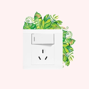 Close-up of white 86 type wall socket and switch with tropical green leaves wall sticker
