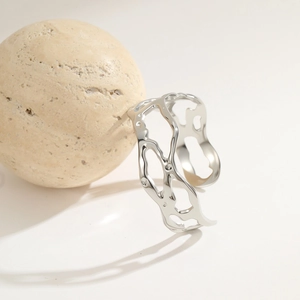 Detail of silver stainless steel open bangle with artistic hollow floral geometry