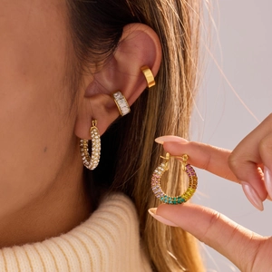 Elegante gouden oorbellenset met regenboog zirkonia en ear cuffs op het oor