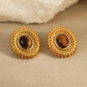 Nahaufnahme vintage goldene Ohrringe mit Tigerauge-Stein und radialer Textur