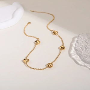 Dettaglio della collana cuore oro a doppio strato con pendenti lucidi su base in pietra