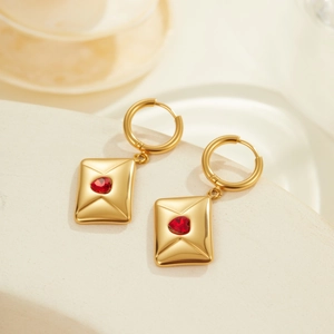Détail de boucles d'oreilles enveloppe en or avec cœur rouge sur présentoir