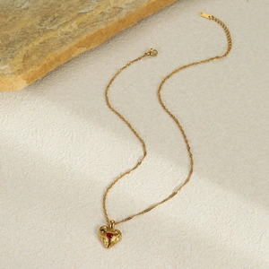 Vue détaillée du collier cœur doré avec zircon rouge et pendentif au design de lave