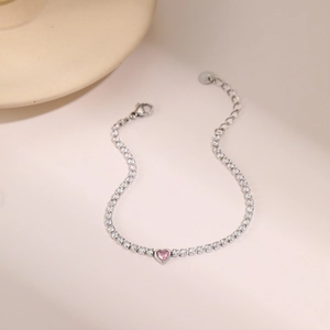 Vista macro detallada de una pulsera plateada con piedra de corazón rosa y circonitas