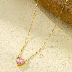 Detalle de collar en oro de 18K con gema rosa en forma de corazón y engaste de 3 garras