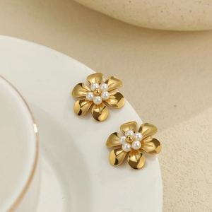 Boucles d'oreilles fleurs dorées avec petites perles blanches sur une tasse en céramique