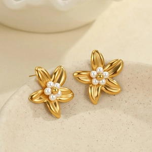 Boucles d'oreilles fleurs dorées avec centres en perles sur un support céramique