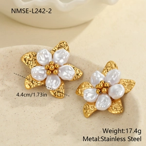 Détail de grandes boucles d'oreilles fleurs en acier avec pétales de perles blanches