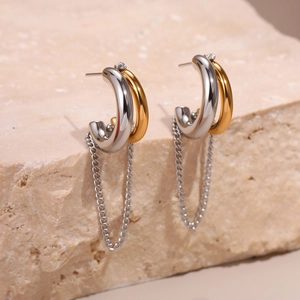 Détail de boucles d'oreilles anneaux dorés et argentés avec longues chaînes à glands