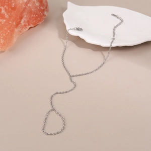 Vista dettagliata del bracciale ad anello in argento con maglie su sfondo beige caldo
