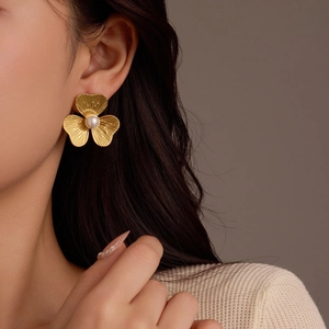 Nahaufnahme eleganter goldener Blumenohrstecker mit Perle am Modell für Schmuckpräsentation