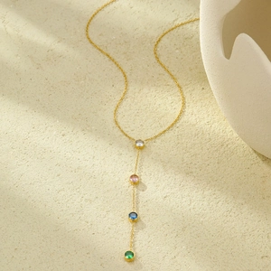 Detalle del collar en Y dorado con cuatro colgantes redondos de circonita de colores