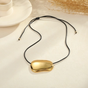 Minimalist gold pebble pendant necklace on black adjustable cord with polished finish