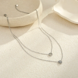 Detalle de collar doble plateado con colgantes de círculos pavé brillantes